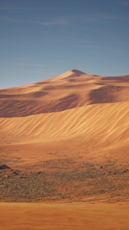 A vast desert landscape featuring dry terrain with a towering mountain in the background under a clear sky.の写真素材