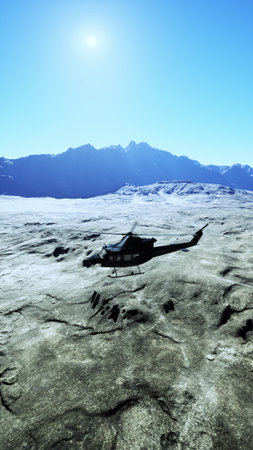 A classic military helicopter rests on a vast expanse of snow amid rugged mountains, basking in the chilly sunshine.の写真素材