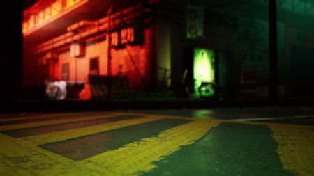Neon colors illuminate a wet street in an evening urban setting. The reflections create an artistic display, capturing the vibrant energy of the city life along an empty road.の写真素材