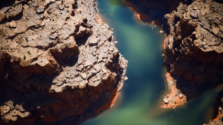 This captivating scene showcases a winding river flowing through a rugged canyon. Sunlight highlights the colorful rocky formations, creating a breathtaking display of natures beauty.の写真素材