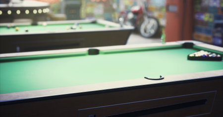 Two billiard tables with vibrant green felt are set up in a bustling game area. Players engage in friendly matches while excitement fills the air in the evening.の写真素材