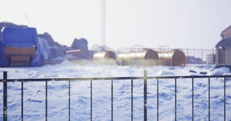 A snowy construction site features blue tarps covering materials and several metal containers...