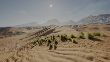 Golden sand stretches across the scene, gentle hills rise under the midday sun, while sparse green grasses add life. Distant mountains create a tranquil horizon, enhancing the beauty of nature.の写真素材