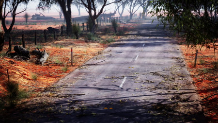 A serene dirt road stretches through a arid landscape, framed by tall trees. The soft light of the evening casts a warm glow, creating a peaceful atmosphere in nature's embrace.の写真素材