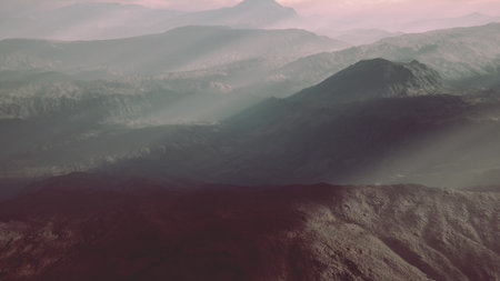 Mountains rise dramatically against a twilight sky, enveloped in soft mist. The landscape glows with warm hues, creating a serene atmosphere. Shadows dance between peaks, inviting exploration.の写真素材