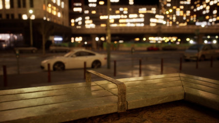Softly illuminated city lights twinkle against a dark sky. A simple bench lined with metal overlooks a quiet street, where vehicles are parked, creating a peaceful urban atmosphere at night.の写真素材