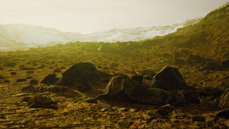 A vast and desolate terrain is scattered with large, dark rocks. The soft light of dusk creates a warm ambiance, illuminating the surrounding hills and distant ice.の写真素材