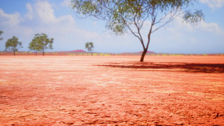 A stretch of parched red earth holds a lone tree against the backdrop of a vibrant blue sky. The...