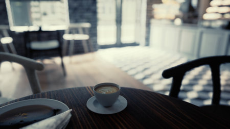 A person relaxes with a warm cup of coffee on a wooden table. Sunlight brightens the charming cafe, creating a cozy atmosphere. Pastries are nearby, inviting a sweet treat.の写真素材