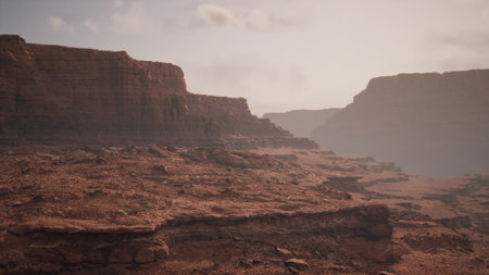 An expansive desert scene unfolds under soft early morning light, showcasing towering cliffs and rocky formations. The warm hues paint a tranquil atmosphere, inviting exploration and wonder.の写真素材