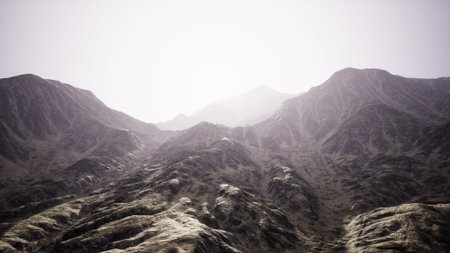 Stunning mountain range rises dramatically against a soft, glowing sky. The rugged terrain reflects early morning light, casting gentle shadows across the surfaces.の写真素材