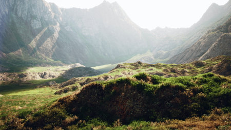 Bright sunlight highlights the verdant valleys and rugged mountains, creating a stunning landscape. The hills are alive with green grass, showcasing natures vibrant colors in perfect harmony.の写真素材