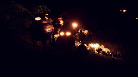 Soft candlelight escapes from intricately designed pots, illuminating a tranquil outdoor setting....