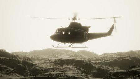 A helicopter hovers above rugged mountain terrain, surrounded by a veil of fog as dawn breaks. The soft light casts an ethereal glow, highlighting the contours of the landscape.の写真素材