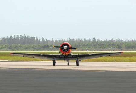 Old propeller airplane taxiing on the ground in front view
