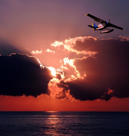 Seaplane soaring over the ocean at sunsetの写真素材