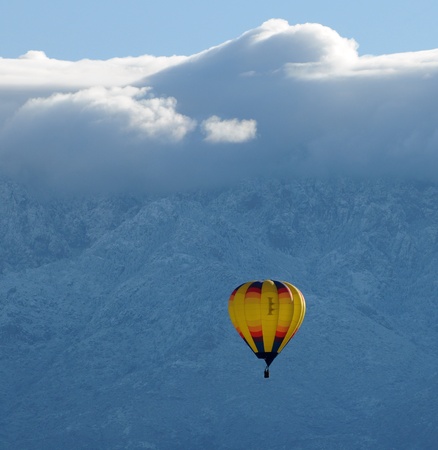 Colorful hot air balloon in midair against snowy mountainの写真素材