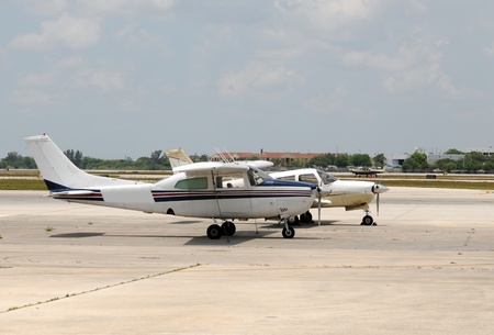 Two light private airplanes parked on a tarmac