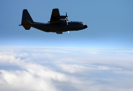 Modern US military cargo airplane flying above the clouds
