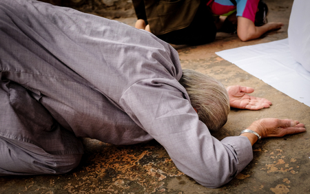 Buddhist worshipper praying, kneeling, and bowing to pay respect at the Buddhist sacred site in India.の写真素材