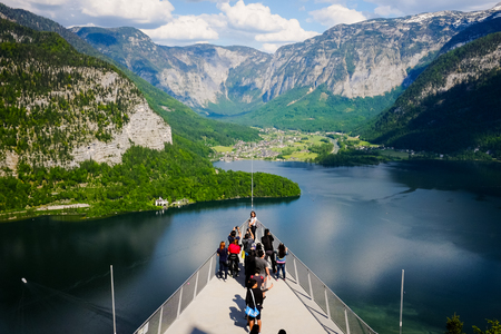 HALLSTATT, AUSTRIA - MAY 18, 2017: Tourists enjoy taking photos of the spectacular aerial view of the lakeside villages and mountain range at the World Heritage Viewing Platform in Hallstatt, Austria.のeditorial素材