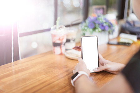 Asian girl use the blank screen smartphone in coffee shop.の写真素材