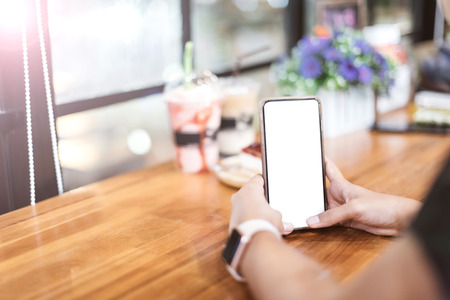Asian girl use the blank screen smartphone in coffee shop.
