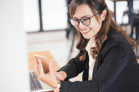 Asian young business freelance woman happiness working online business with laptop and cell phone in cafe shop. Working concept.の写真素材