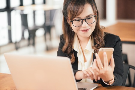 Asian young business freelance woman happiness working online business with laptop and cell phone in cafe shop. Working concept.の写真素材