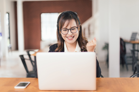 Asian young business freelance woman happiness working online business with laptop and cell phone in cafe shop. Working, Success, happiness concept.の写真素材