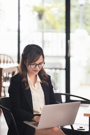Asian young business freelance woman happiness working online business with laptop and cell phone in cafe shop. Working concept.の写真素材
