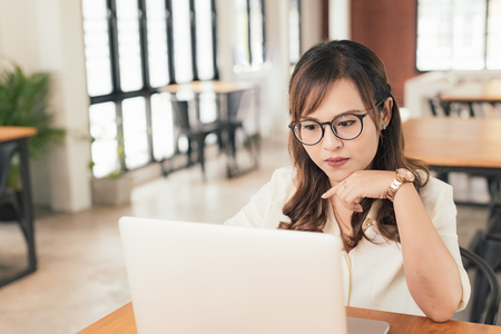 Asian young business freelance woman concentrate working online business with laptop and cell phone in cafe shop. Working, Success, concentrate concept.の写真素材