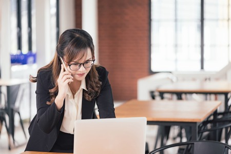 Asian young business freelance woman happiness working online business with laptop and cell phone in cafe shop. Working concept.の写真素材