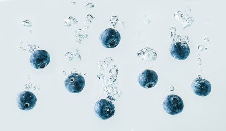 Blueberries sinking into water with air bubbles background