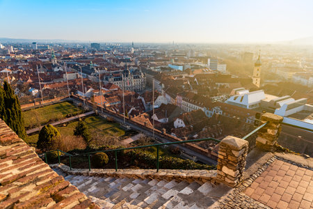 Graz, Styria / Austria - 20.01.2019: View at Graz City from Schlossberg hill,garden, Town hall, Mur river and city center, clock tower Sun on the winter blue sky. Travel destination.