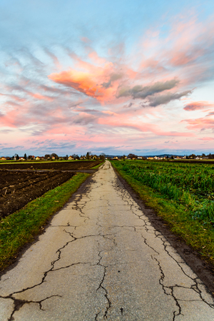 Sunset over fields and Austrian village with dramatic sky and colorful clouds. Country road in Austriaの写真素材