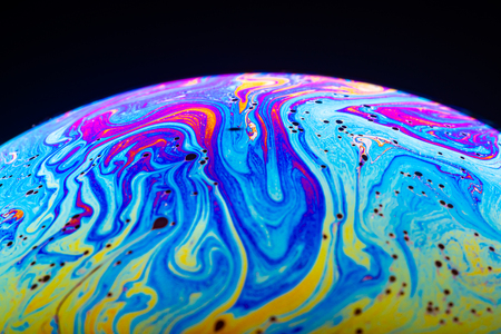 Abstract background made from soap bubble reflecting light. Rainbow soap bubble on a dark background.の写真素材