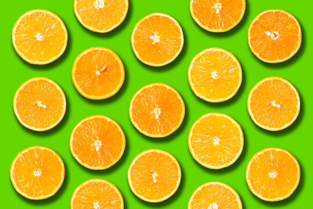 Background of half cut organic oranges on green background