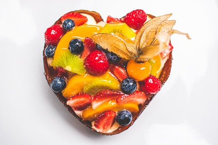 Heart shaped fruit sponge cake, Fruit Tart on white background on table. Healthy confectionery background.の写真素材