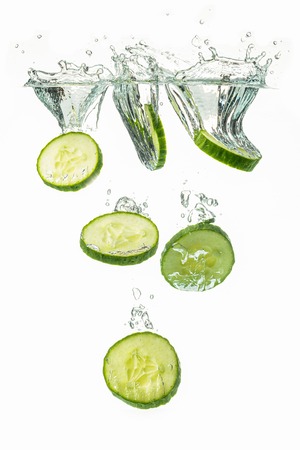 Sliced cucumber splashing water isolated on white background. Vertical photo. Skin moisturizing cosmetics conceptの写真素材