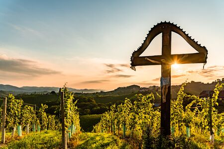 Christian wooden cross with figure of Jesus Christ on Vineyards at Slovenia - Austria border near famous tourist destination of heart shaped road.の写真素材