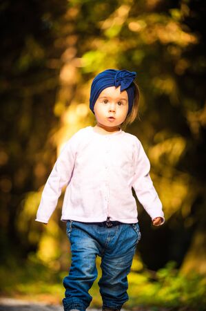 Portrait of 2 years old baby girl in forest walking by herself. Not wanting to follow parents. Concept of child independence.の写真素材