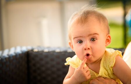 Portrait of cute baby outdoors with funny expression. Copy space on left. Background