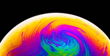 Rainbow soap bubble on a dark background. Close-up of colorful surface. Psychedelic colors.