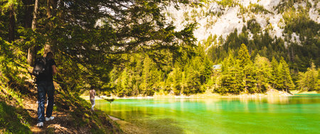 Gruner See, Austria 16.05.2017: Peaceful mountain view with famous green lake in Styria. Turquoise green color of water. Tourists walking on the shore. Travel destinationのeditorial素材