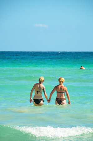 Alcudia, Spain 14.09.2011 - A couple holding hands in the sea. Two womans couple enjoying summer sun on vacation. Mallorca island famous tourist destination.のeditorial素材