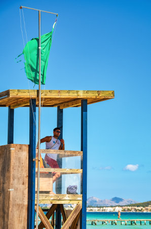 Alcudia, Spain 14.09.2011 - Lifeguard in booth observing people swimming at Playa de Muro beach. Mallorca island famous tourist destinationのeditorial素材