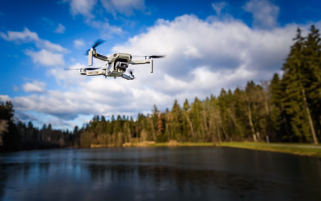 Graz, Austria - December 29 2019. DJI Mavic Mini drone flying in the countryside above frozen lake on sunny winter dayのeditorial素材