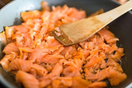 Pan with Pile of Cut Salmon Pieces, on stove. with wooden spoon. Healthy food.の写真素材