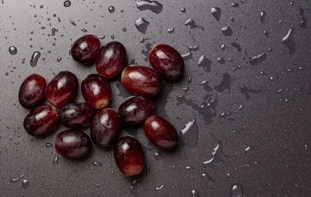 Close up of red grapes on black background with copy space. Water droplets, washing concept